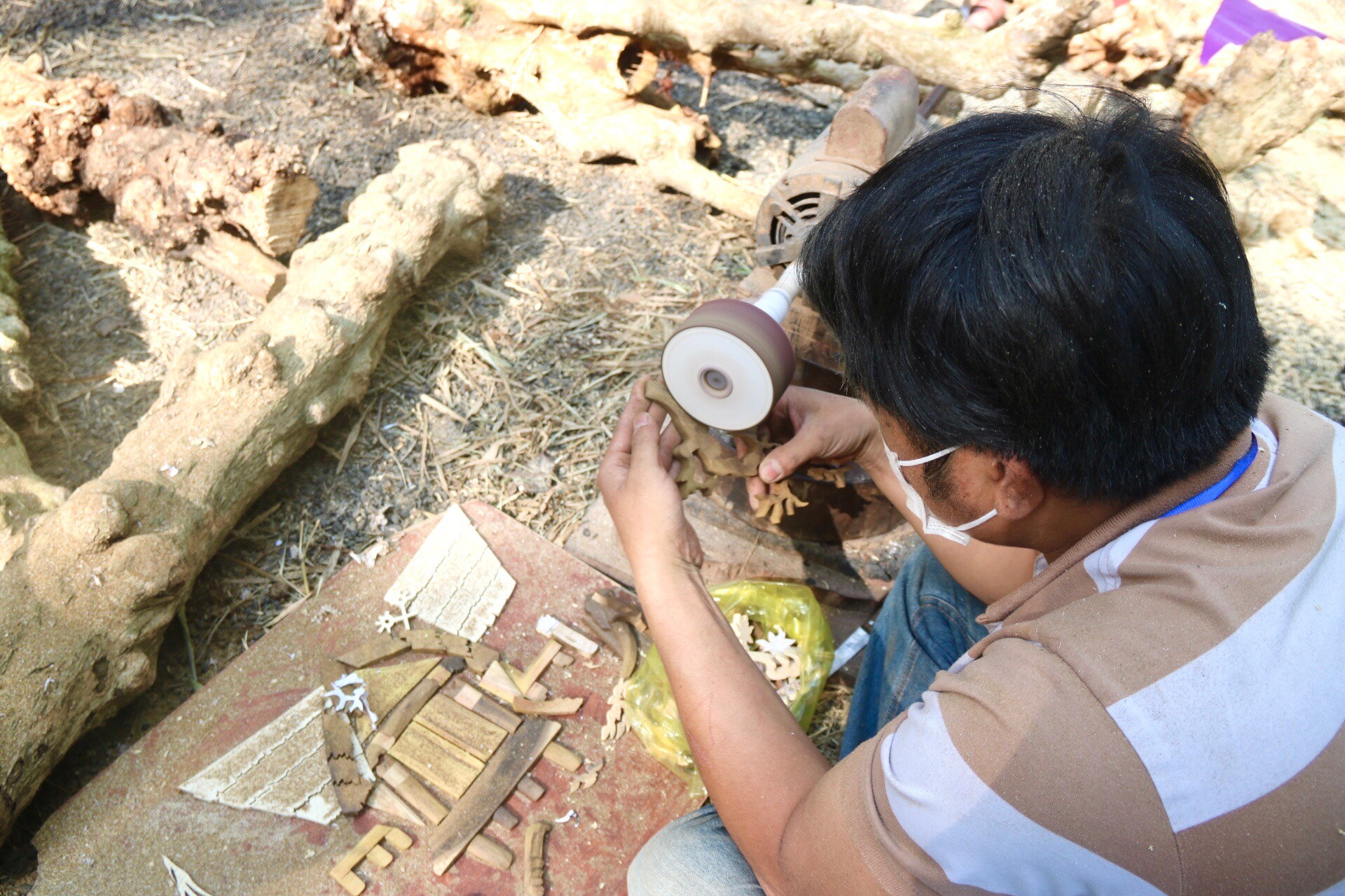 Nghệ nhân (TP. Buôn Ma Thuột, tỉnh Đắk Lắk) tỉ mỉ mài những chi tiết nhỏ cho bức tranh từ thân gỗ cà phê của mình. 