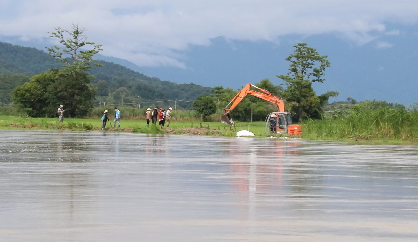 Lực lượng chức năng phối hợp với người dân gia cố đoạn đê sông Krông Na bị vỡ. Ảnh: Quang Yên.