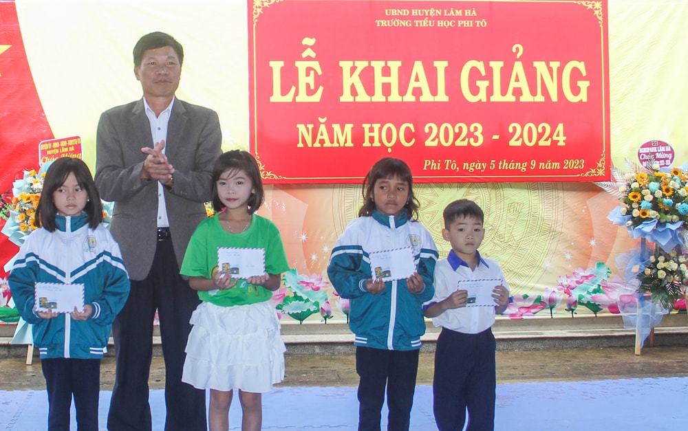 Đồng chí Nguyễn Văn Tân - Chủ tịch HĐND huyện Lâm Hà trao quà cho học sinh
