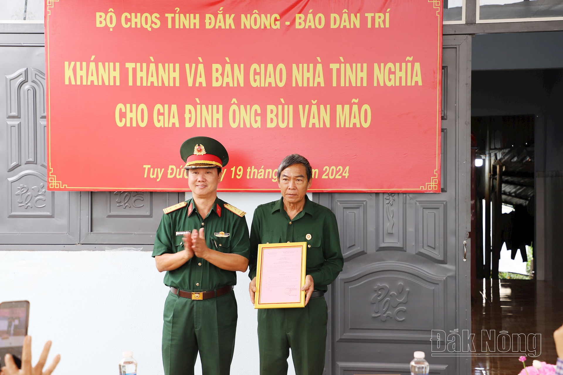 Thượng tá Đặng Văn Tiến, Phó Chủ nhiệm Chính trị Bộ Chỉ huy Quân sự tỉnh Đắk Nông trao quyết định bàn giao căn nhà cho cựu chiến binh Bùi Văn Mão (bên phải)