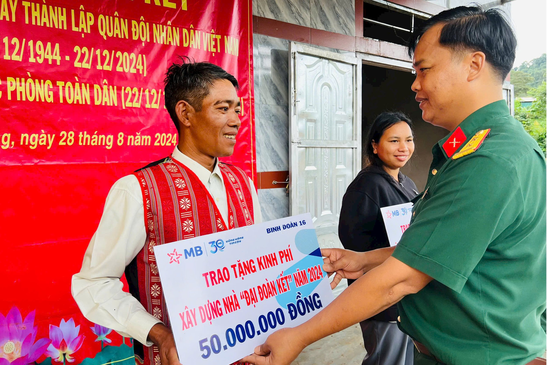 Trung tá Đỗ Văn Tráng, Bí thư Đảng uỷ Trung đoàn 726 trao kinh phí hỗ trợ xây dựng nhà đại đoàn kết cho ông Điểu Nu, bon Bu P’Răng 1A, xã Quảng Trực, huyện Tuy Đức (Đắk Nông)