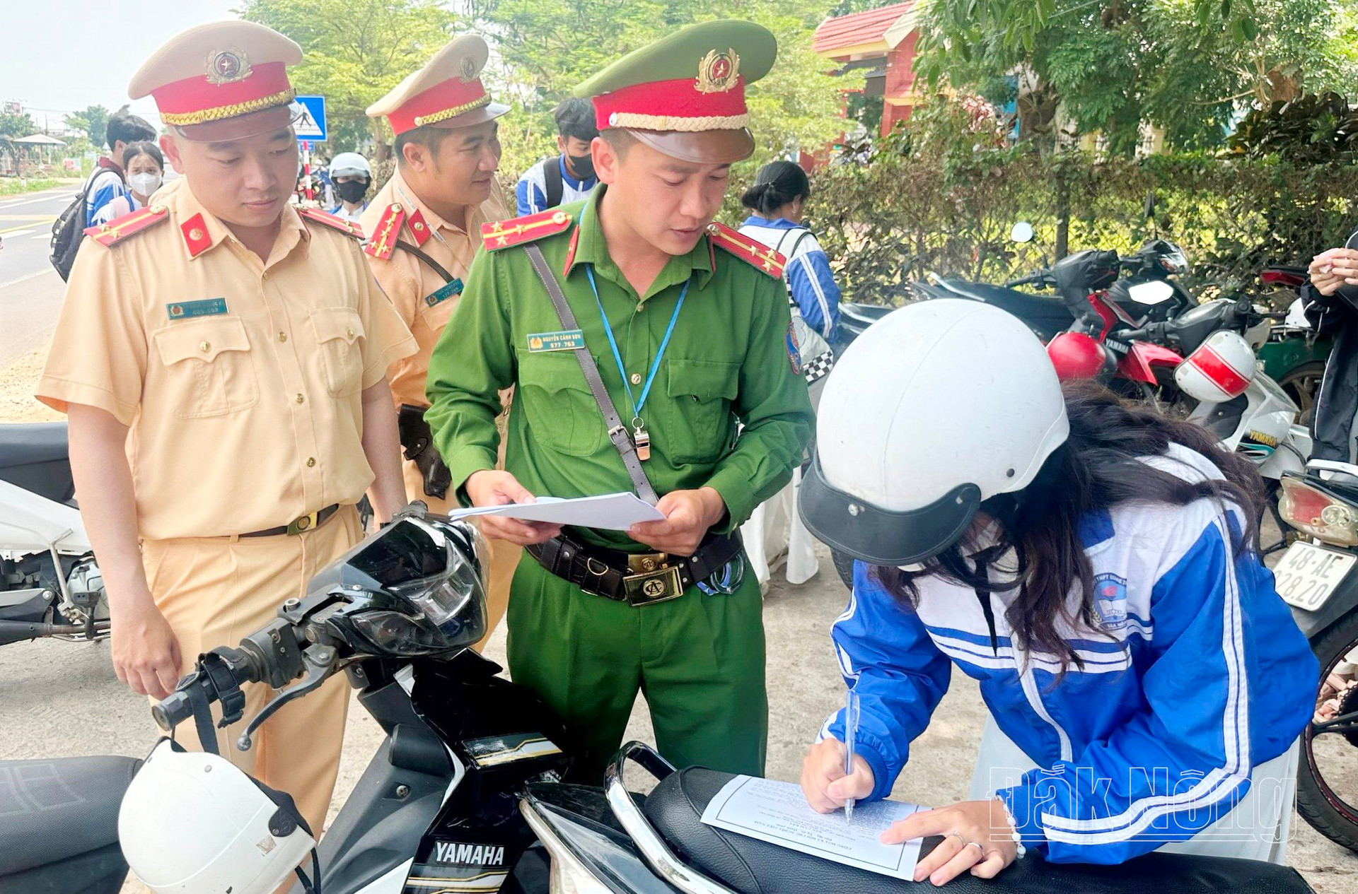 Lực lượng chức năng huyện Đắk Mil cho học sinh ký cam kết chấp hành Luật ATGT ngay cổng trường học