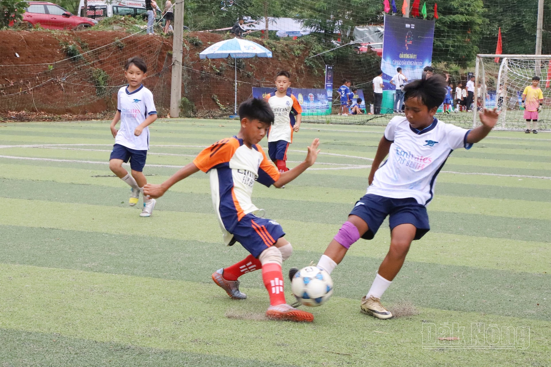 Cầu thủ 2 đội tranh chấp bóng bên phần sân của U11 Đắk Glong