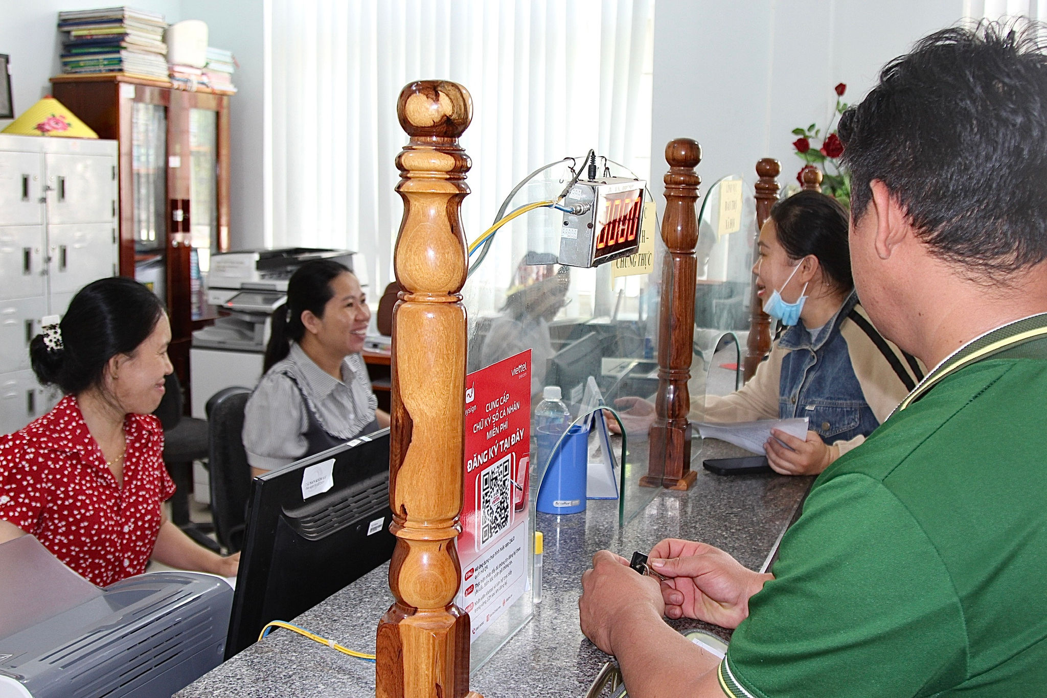 Cán bộ Trung tâm phục vụ hành chính công xã Tân Lập vui vẻ trao đổi với người dân