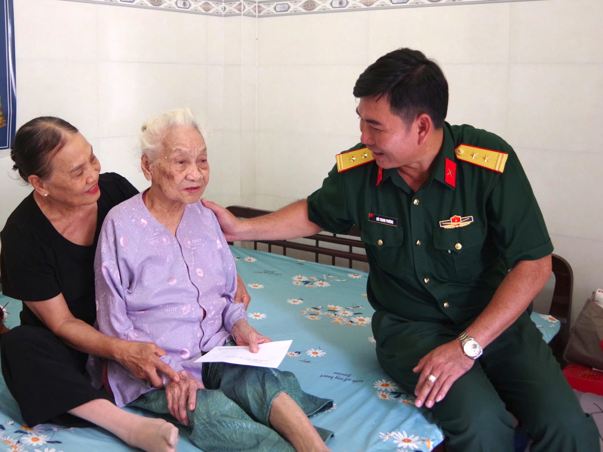Trung tá Bùi Thanh Phương, Phó Chính ủy Ban Chỉ huy Phòng thủ khu vực 5 - Phan Thiết thăm, tặng quà Mẹ Việt Nam anh hùng Từ Thị Đinh ở khu phố Phú Xuân, phường Hàm Thắng, tỉnh Lâm Đồng.