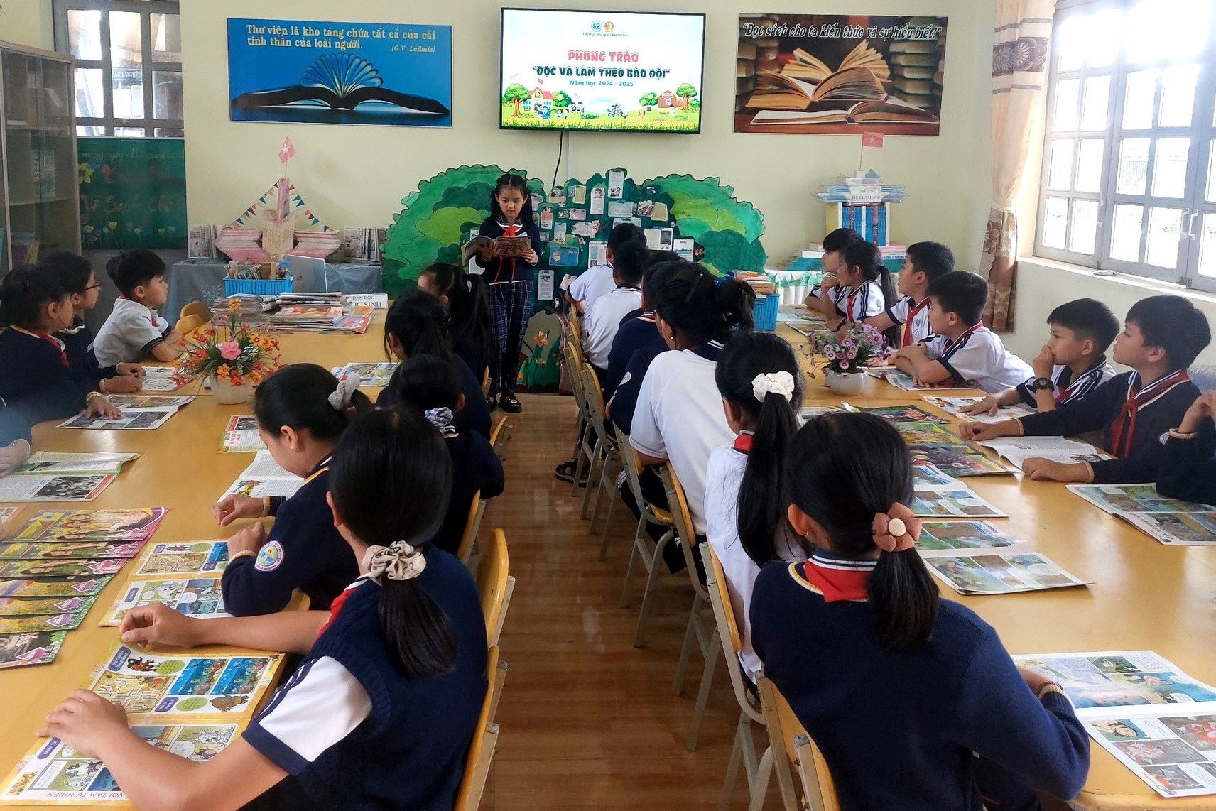 Buổi đọc báo toàn trường tại thư viện, học sinh luân phiên đọc và chia sẻ câu chuyện từ báo Đội