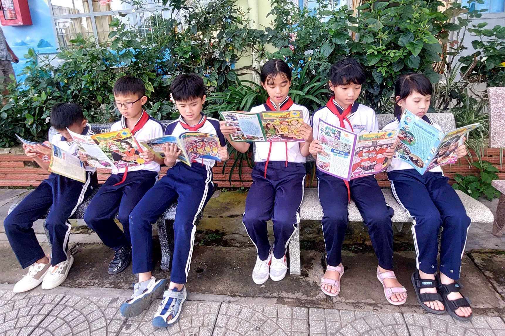Không gian đọc ngoài trời, dưới tán cây, tạo môi trường thư giãn nhưng vẫn tập trung cho học sinh đọc báo.