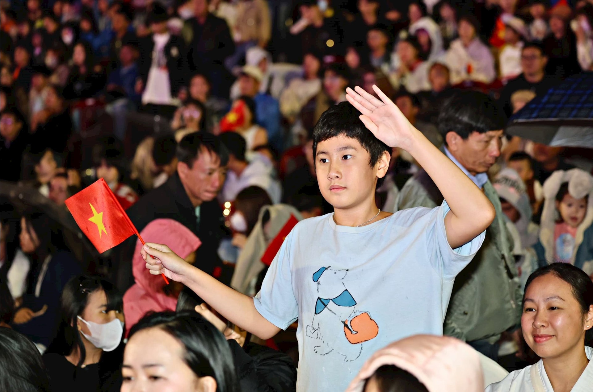 A child raises his hand in a military salute, expressing pride as artists and actors reenact scenes of the Vietnam People's Army fighting.