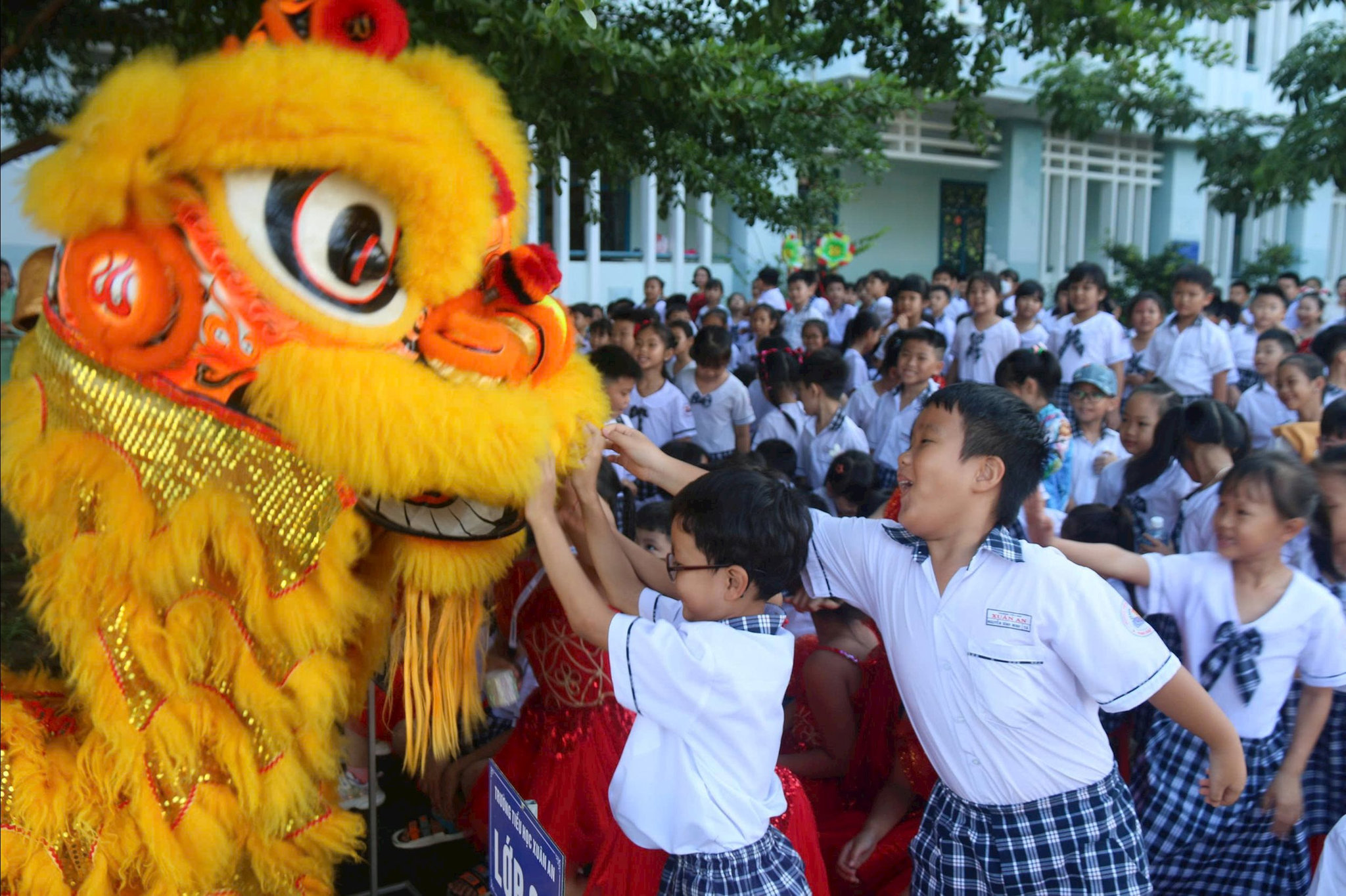 Học sinh tiểu học vui mừng đùa giỡn với đội múa lân