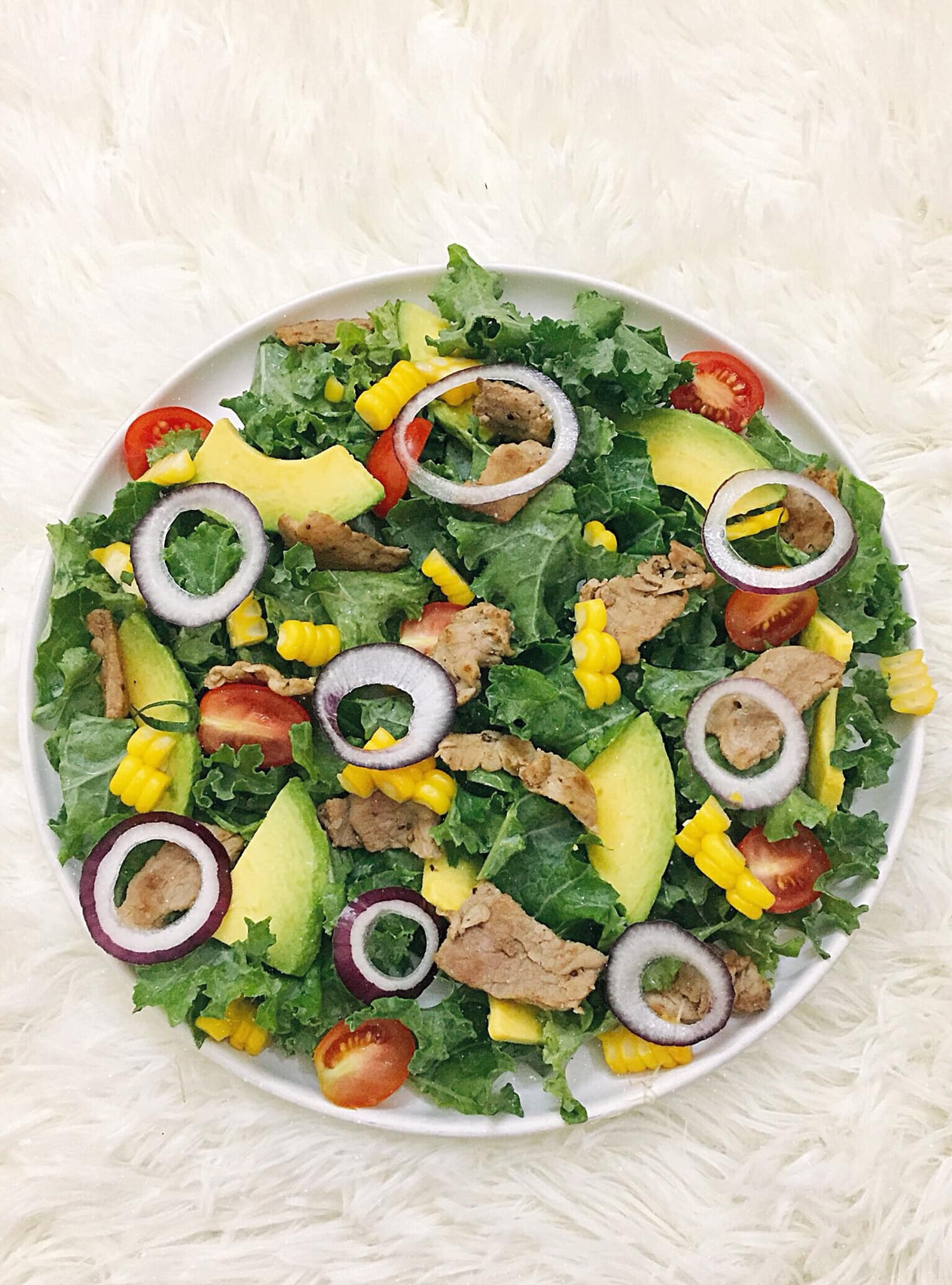 Món salad gồm cải kale, bơ, ngô ngọt, thịt bò, hành tím, cà chua bi.