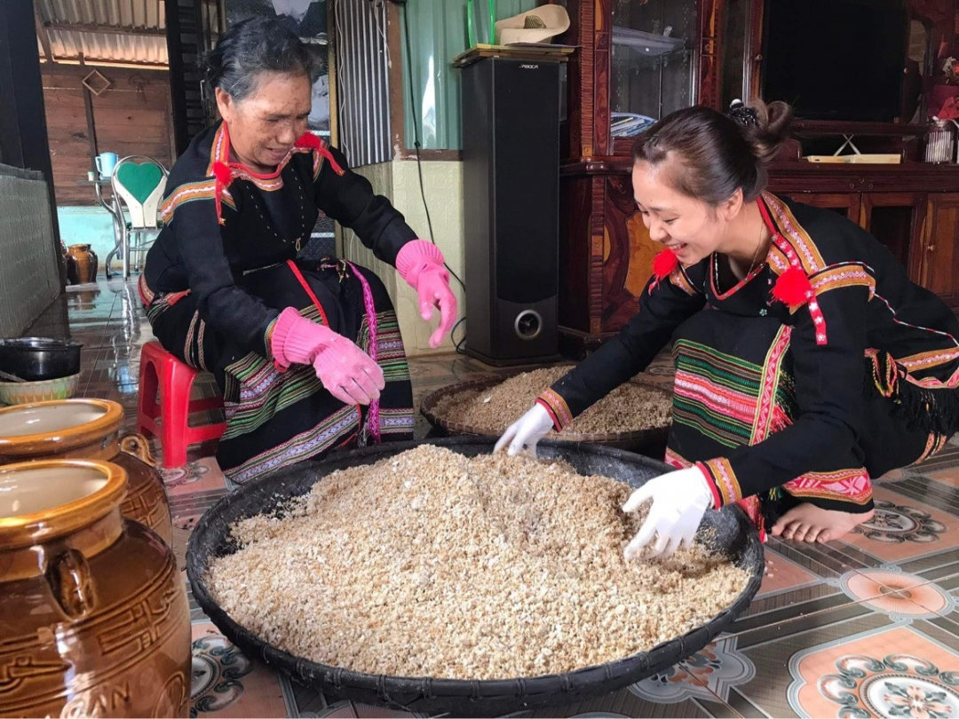 Bà H’Căn Ayun truyền nghề ủ rượu cho cháu gái.