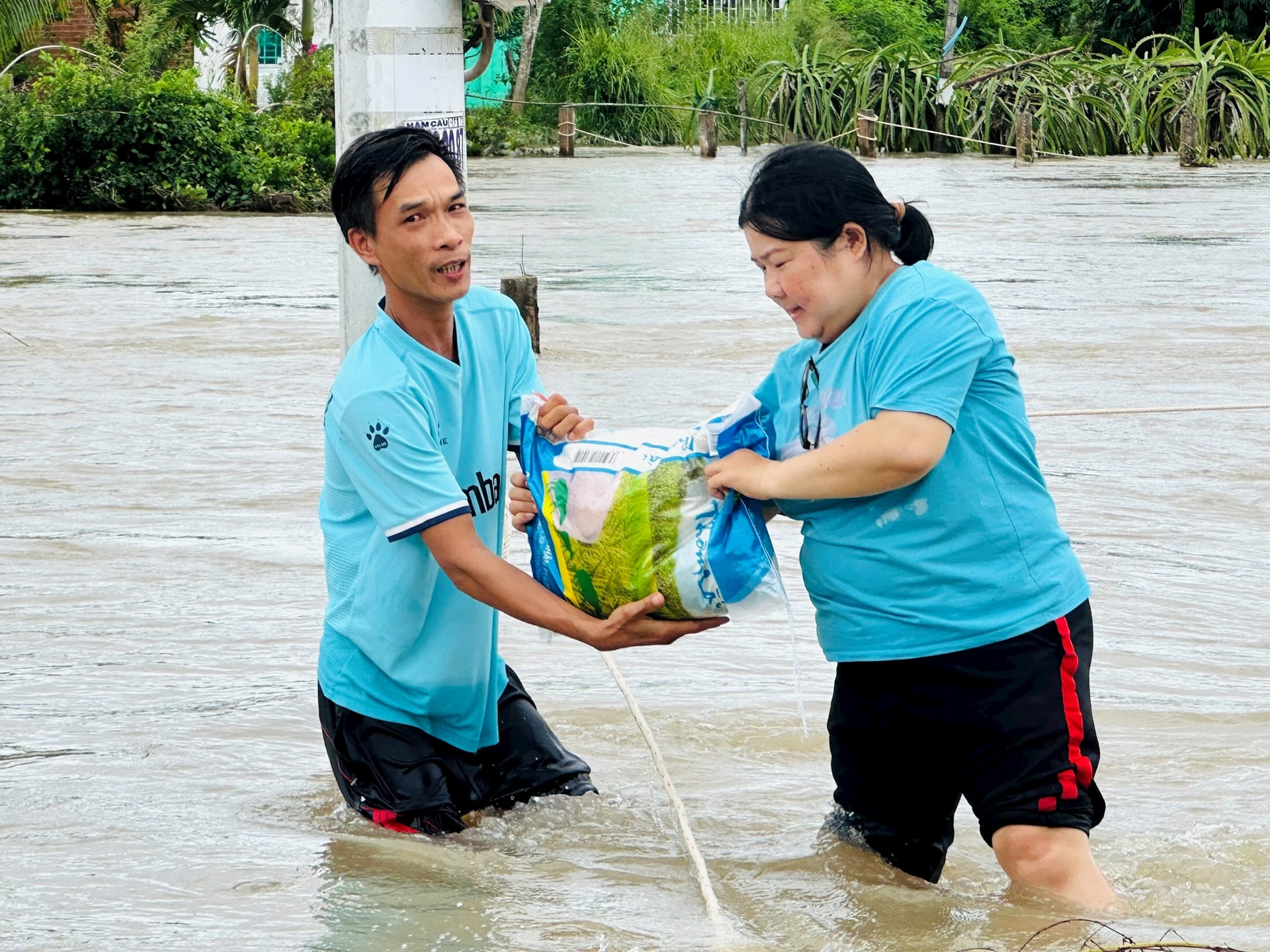 ຜູ້ໃຈບຸນ (ຂວາ) ສະໜັບສະໜູນເຂົ້າໃຫ້ຄອບຄົວທີ່ຖືກນໍ້າຖ້ວມ.