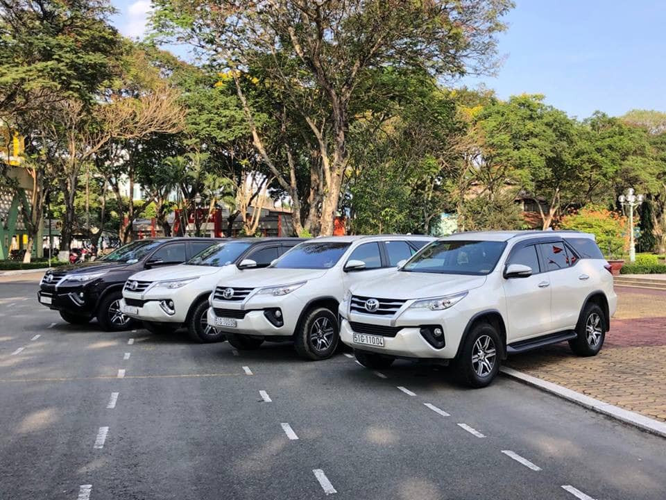 Một chiếc xe ô tô màu trắng đang di chuyển trên đường phố Hà Nội, phù hợp cho việc thuê xe tự lái.