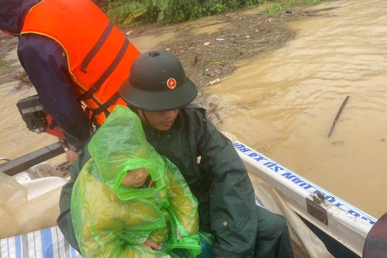 Uma criança com febre alta foi retirada da casa inundada por oficiais do Comando de Defesa da Região 2 - Dong Gia Nghia.