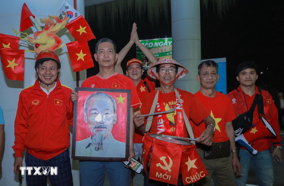 Người hâm mộ mang ảnh Bác Hồ chào đón đội tuyển. (Ảnh: Phan Phương/TTXVN)