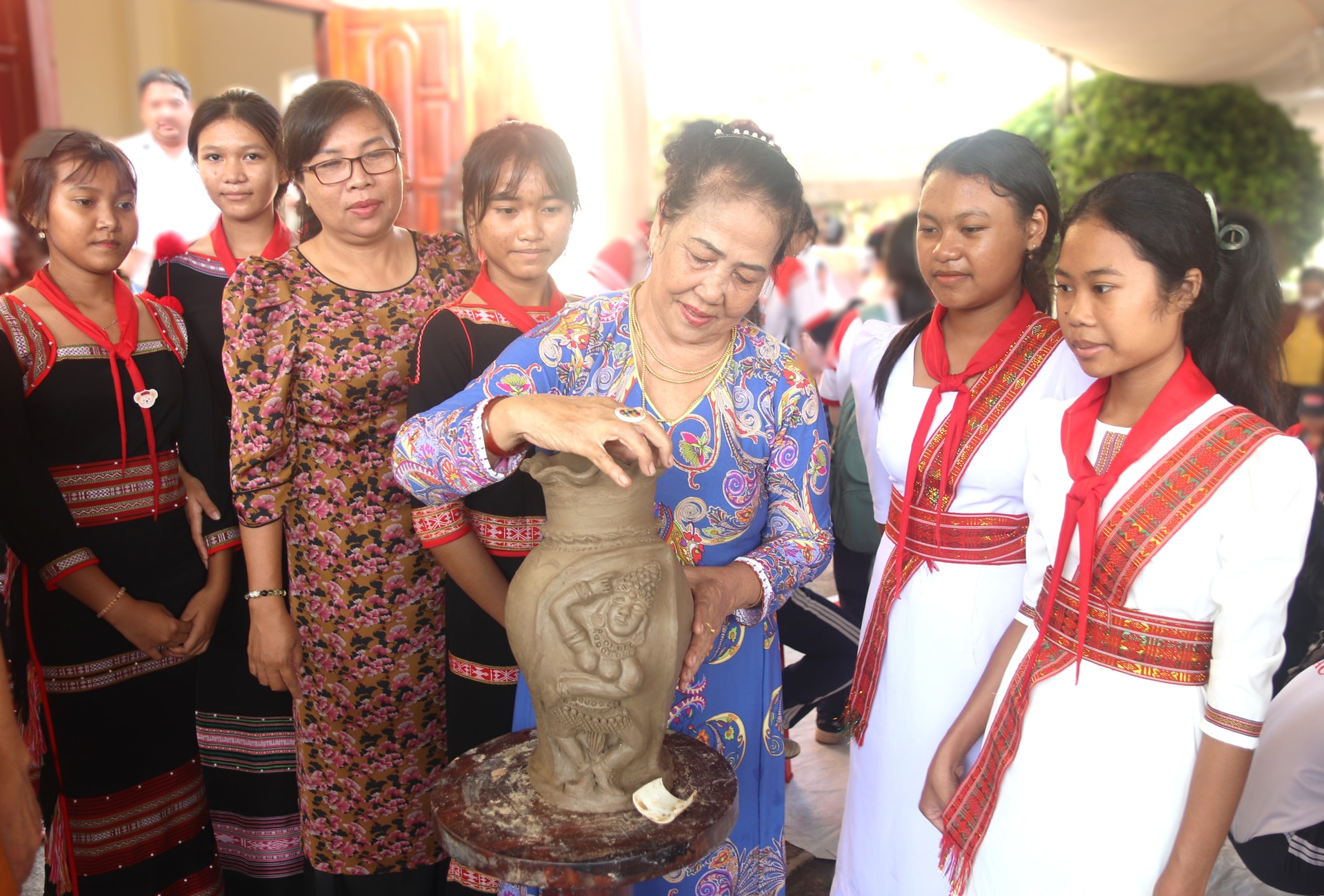Profesorii și elevii îi urmăresc pe artizani demonstrând cum fac olăritul.
