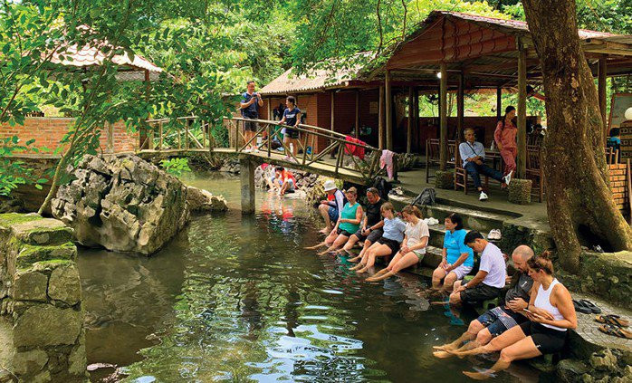 Du khách nước ngoài ngồi thư giãn bên dòng suối tại làng cổ Việt Hải