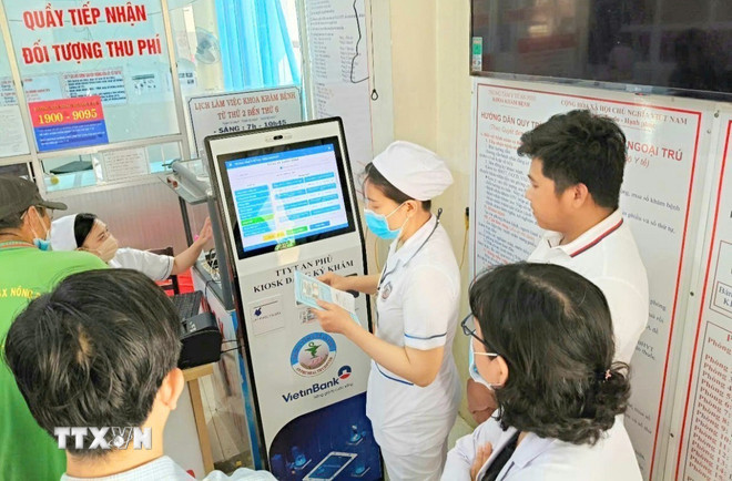 Cán bộ, nhân viên Trung tâm y tế An Phú, An Giang, hướng dẫn người dân đăng ký khám chữa bệnh bằng kiốt thông minh. (Ảnh: Công Mạo/TTXVN) ttxvn-cham-soc-suc-khoe-nhan-dan2.jpg