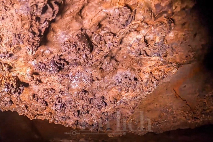 Màu sắc đỏ quạch và lấp loáng của vách hang dưới ánh đèn pin tạo nên khung cảnh vừa hư vừa thực.
