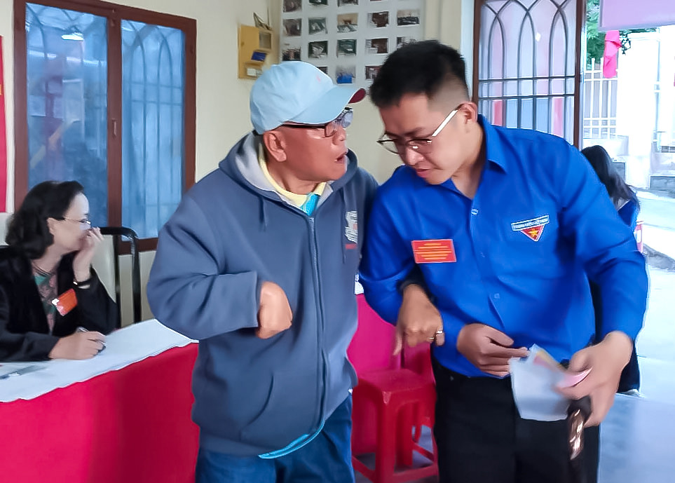 Đoàn viên thanh niên khu vực bỏ phiếu số 12 hỗ trợ người tàn tật lấy phiếu bầu cử