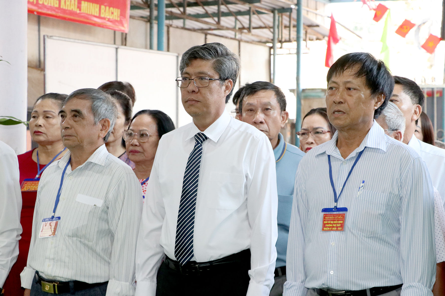 Đồng chí Nguyễn Minh, Tỉnh ủy viên, Phó Chủ tịch UBND tỉnh Lâm Đồng (áo trắng) thực hiện nghi lễ chào cờ tại tạ Khu vực bỏ phiếu số 11 (Khu phố 12, phường Phú Thủy).