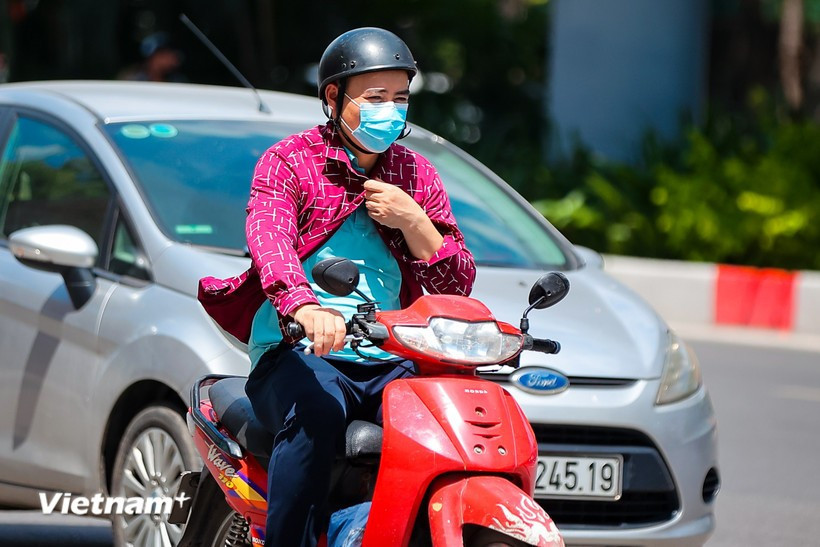Người dân di chuyển dưới trời nắng gắt. (Ảnh: Hoài Nam/Vietnam+)