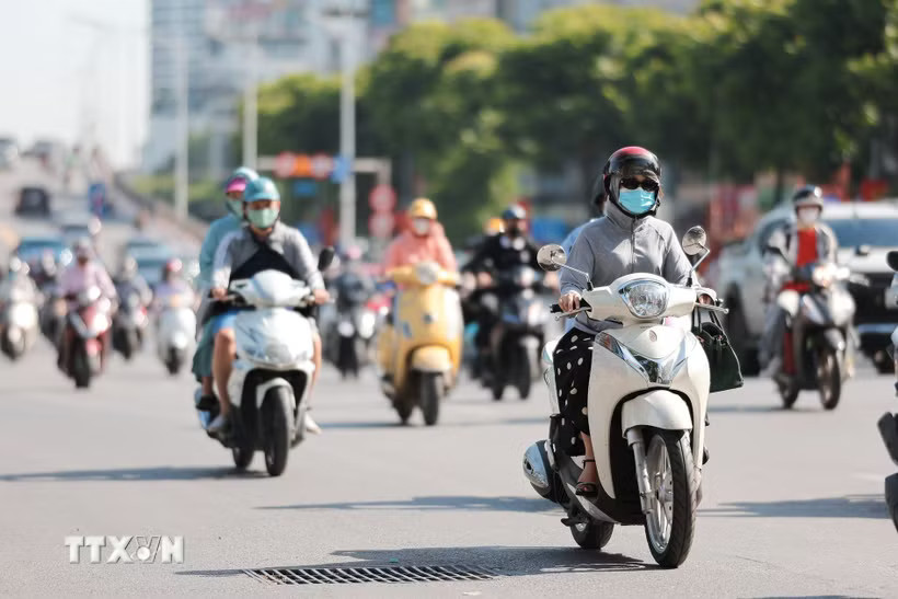 Người dân sử dụng khẩu trang, áo chống nắng giúp tránh nóng bức khi tham gia giao thông. (Ảnh: Lê Đông/TTXVN)