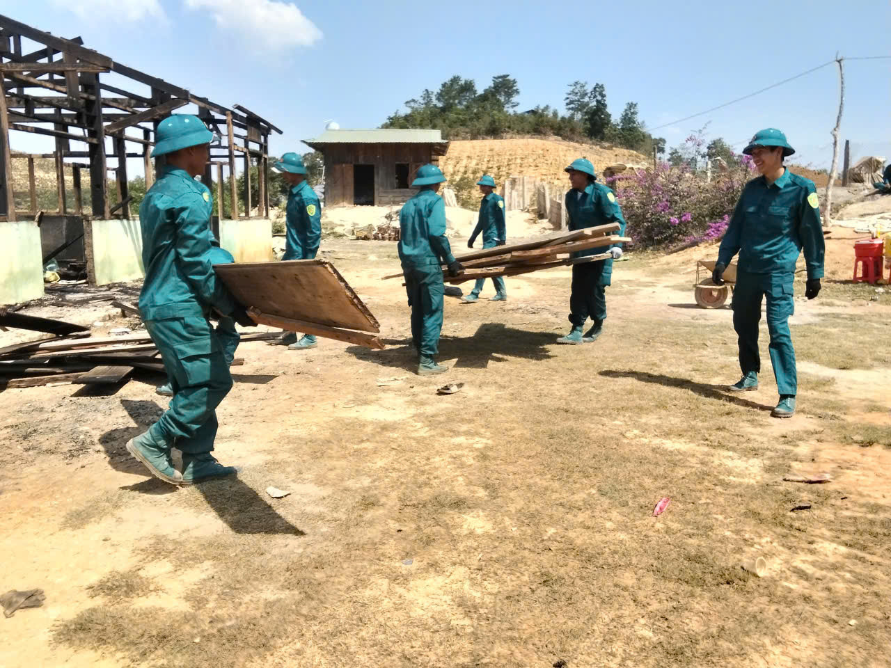 Dân quân tự vệ đang hỗ trợ gia đin dựng lại nha sau vụ hỏa hoạn.