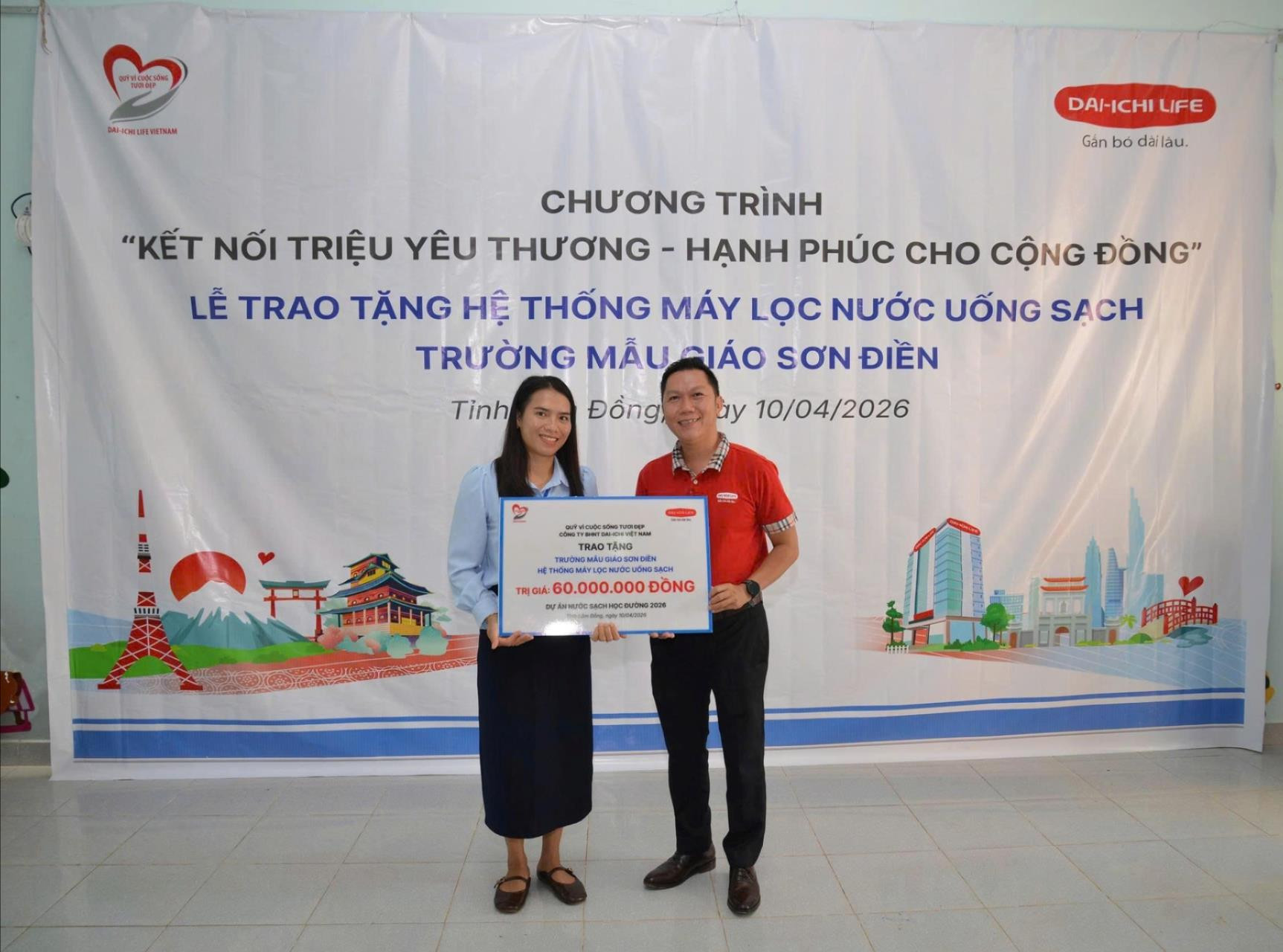 Đại diện Dai-ichi Life Việt Nam (áo đỏ) trao biểu trưng tài trợ hệ thống máy lọc nước uống sạch cho Trường Mẫu giáo Sơn Điền