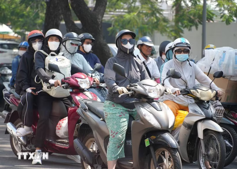 Người dân mặc đồ bảo hộ chống nắng, khi di chuyển trên đường. (Ảnh: Nguyên Lý/TTXVN)