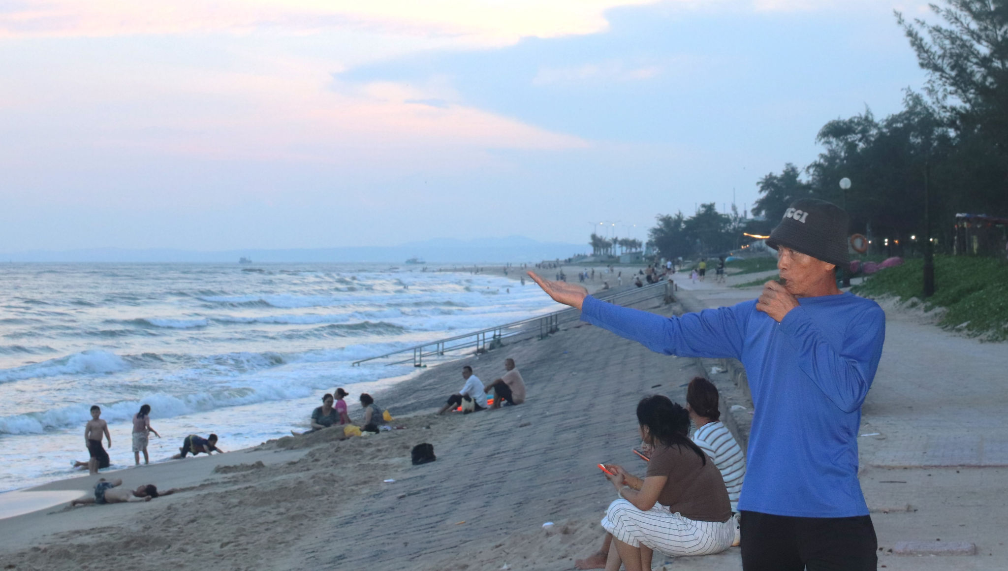 Anh Phan Hữu Đức ra dùng còi và tay báo hiệu du khách không được ra xa khi biển động