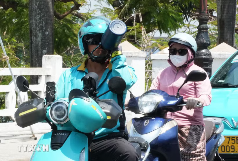 Một lái xe công nghệ ở Huế uống thêm nước khi di chuyển trên đường, để cơ thể tránh mất nước giữa nắng nóng gay gắt. (Ảnh: Nguyên Lý/TTXVN)