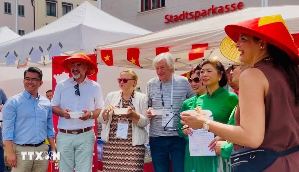 Ông Martin Schenkelberg (đội nón), Trưởng Ban Hội nhập và Xã hội thành phố Augsburg tham quan gian hàng Việt Nam. (Ảnh: TTXVN phát) ttxvn-duc-cong-dong-nguoi-viet-tai-bavaria-day-manh-giao-luu-nhan-dan-8898229-1.jpg