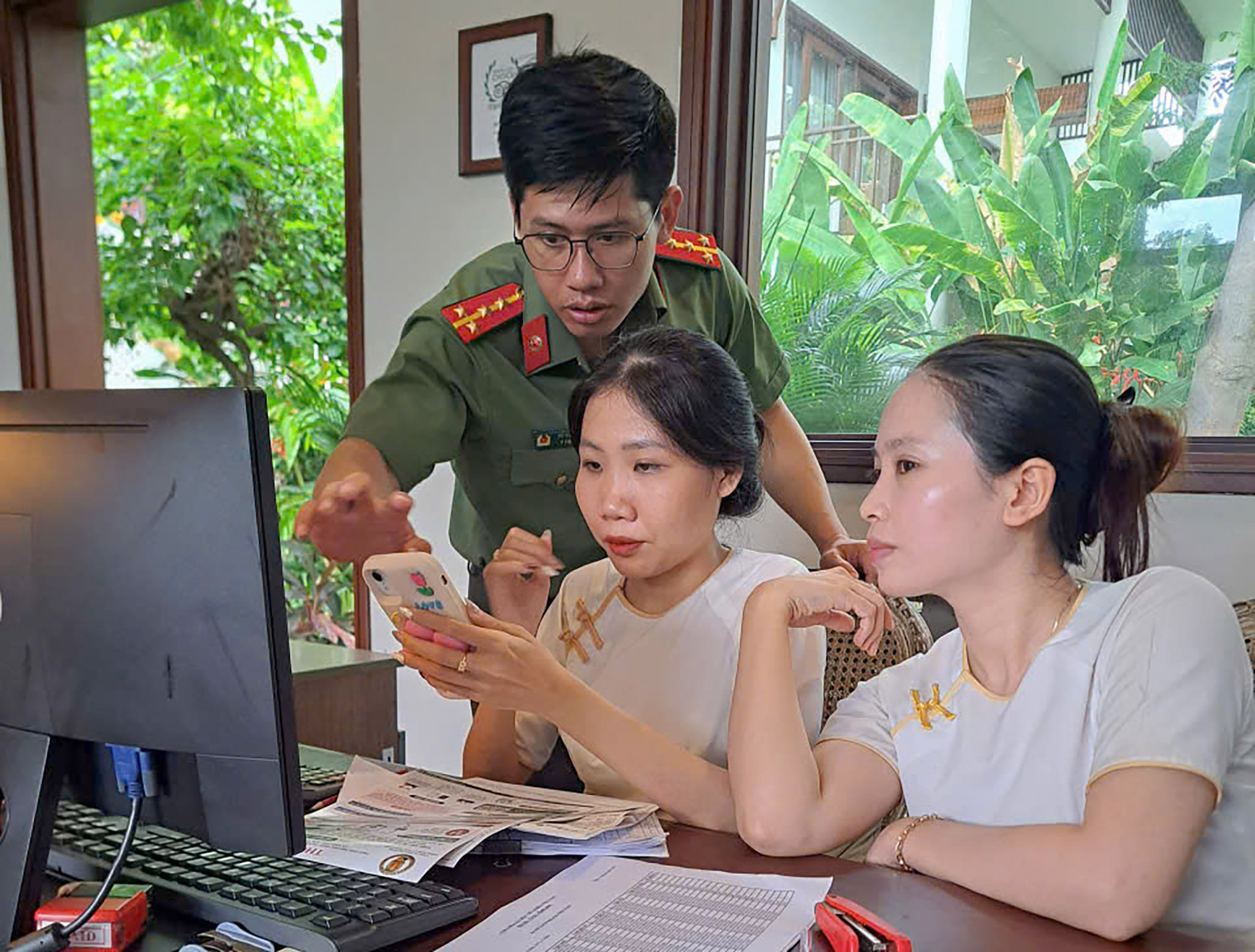 3. Cán bộ Phòng Quản lý xuất nhập cảnh hướng dẫn nhân viên cơ sở lưu trú thực hiện khai báo tạm trú trên thiết bị di động. Ảnh Lê Tiến