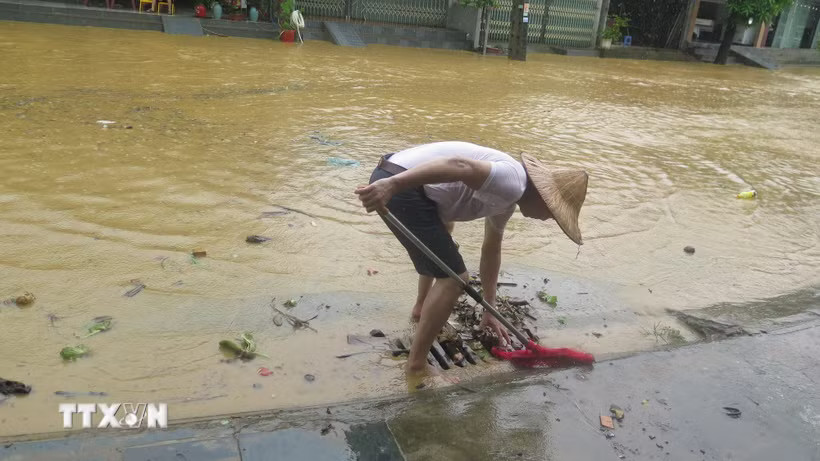 Người dân tổ 4 Duyên Hải, phường Lào Cai khơi thông cống rãnh thoát nước ngập úng. (Ảnh: Hương Thu/TTXVN)