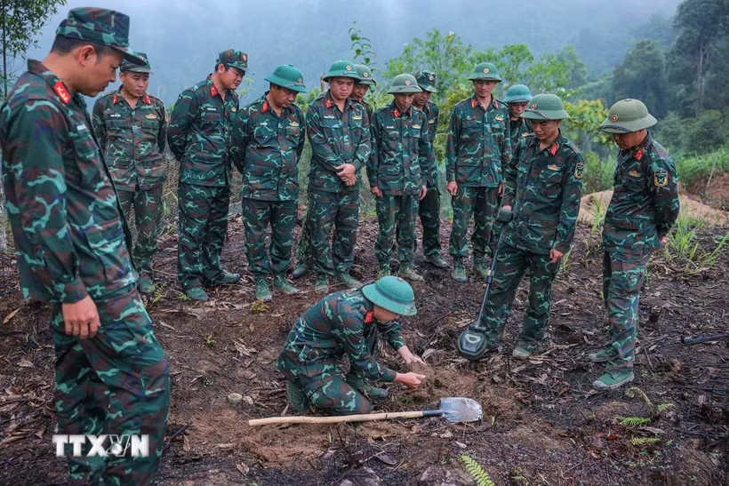 Các thành viên Đội tìm kiếm, quy tập hài cốt liệt sĩ sử dụng máy dò mìn để đảm bảo khu vực tìm kiếm 
