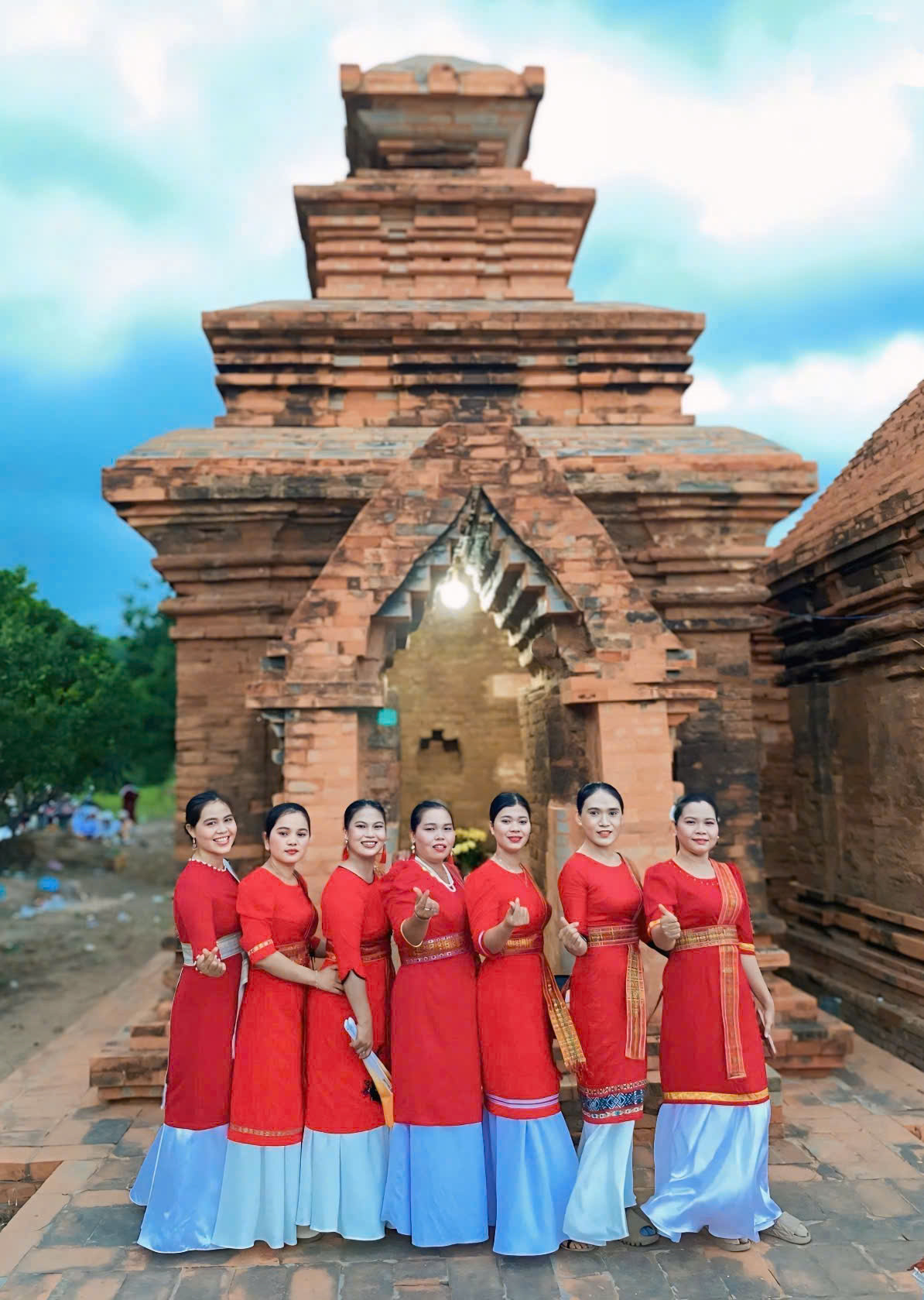 C&aacute;c thiếu nữ Chăm duy&ecirc;n d&aacute;ng trong trang phục truyền thống đỏ thắm check-in b&ecirc;n th&aacute;p Chăm cổ k&iacute;nh.