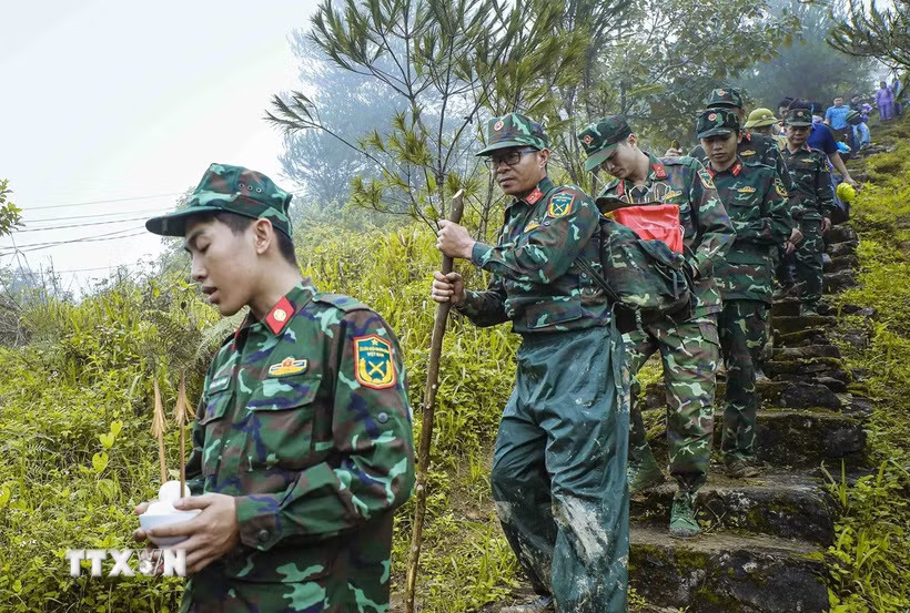 Trên cung đường núi hiểm trở, chiến sỹ cõng hài cốt liệt sỹ xuống núi sau khi hoàn thành công tác quy tập tại bản Lồng, xã Quài Tở, tỉnh Điện Biên. (Ảnh: Xuân Tư/TTXVN)