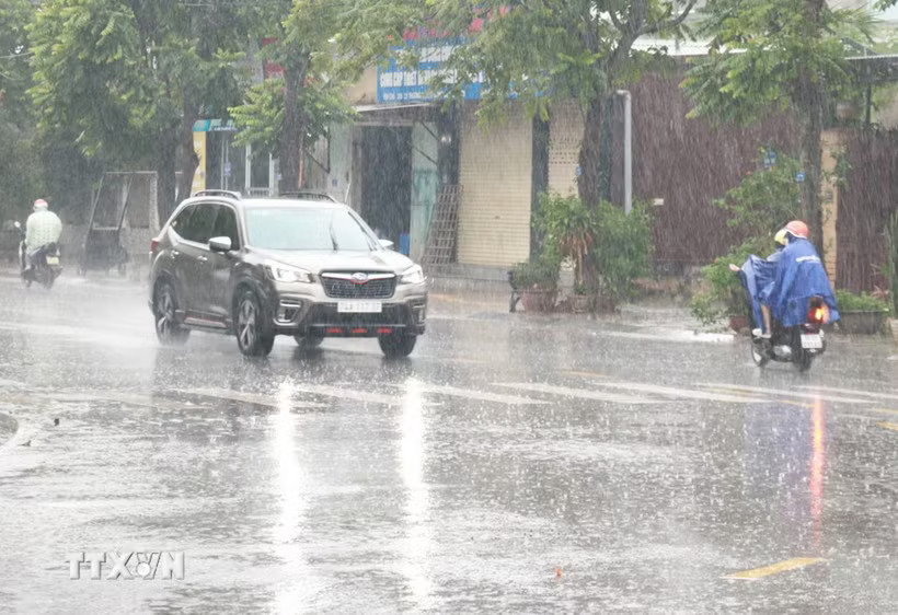 Người dân đi lại trong mưa lớn. (Ảnh: Nguyên Lý/TTXVN)