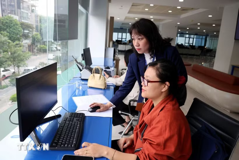 Cán bộ Trung tâm Phục vụ hành chính công thành phố Hà Nội thực hiện giải quyết thủ tục hành chính cho người dân. (Ảnh: Vũ Quang/TTXVN)