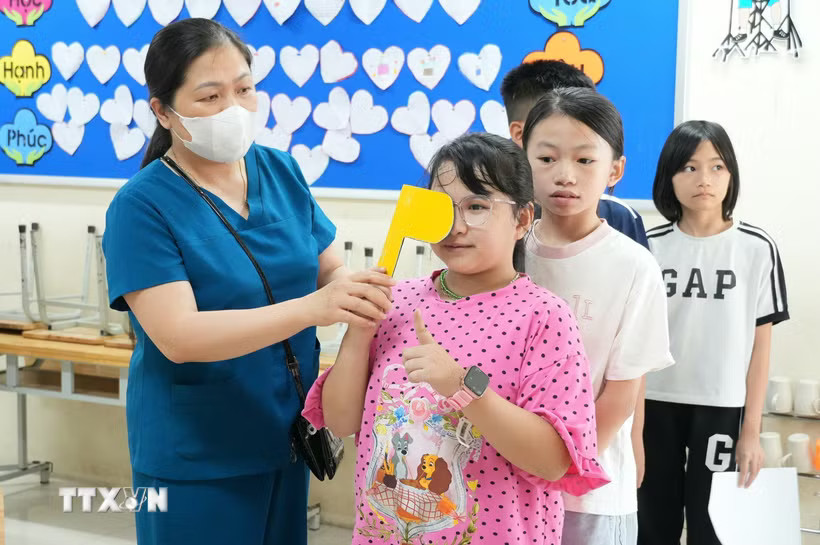 Kiểm tra thị lực cho trẻ em trong chương trình khám khám sàng lọc miễn phí. (Ảnh: TTXVN)