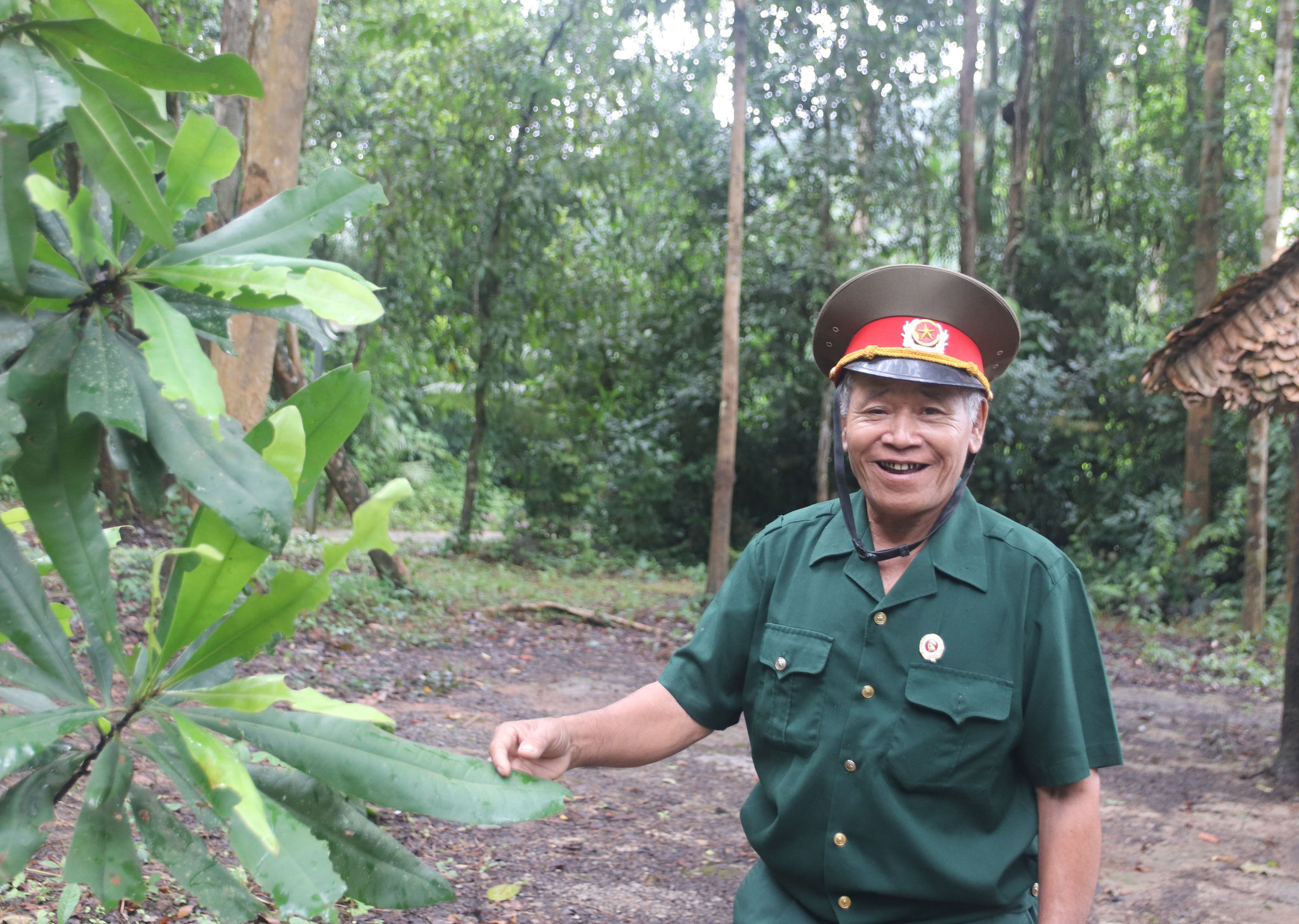 Cựu chiến binh K'Văn Dên đang chia sẻ với đoàn tham quan tại Khu căn cứ về cây trung quân 
