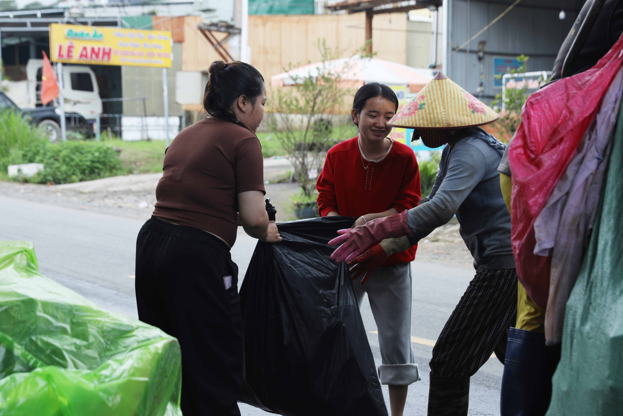 Người dân xã Đam Rông 1 hỗ trợ công nhân thu gom rác đưa rác lên xe chuyên dụng