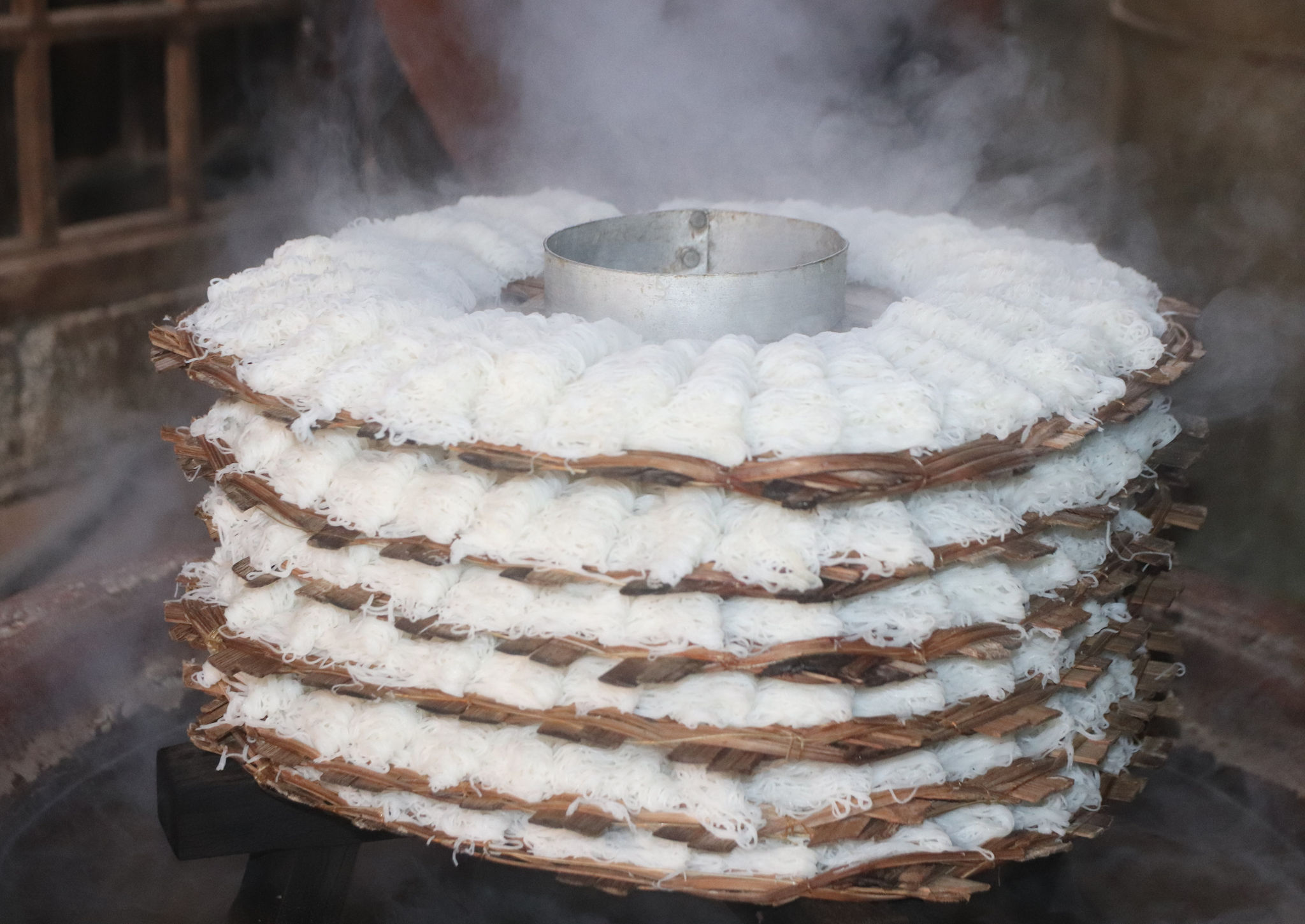 Những sợi bánh được người thợ khéo léo trải lên các khay tròn bằng tre rồi hấp chín